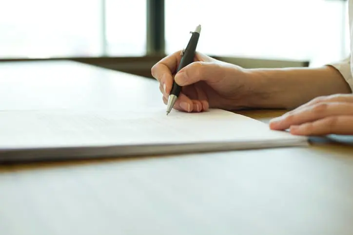 Person signing document, cropped